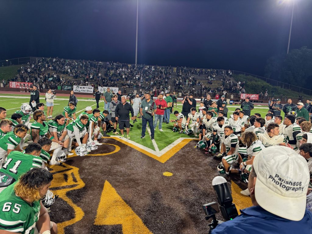 Konawaena (left) and Kapa'a high school football teams await the trophy presentations after Kapa'a's 10-7 overtime win in the First Hawaiian Bank/HHSAA Division I state championship game on Nov. 30, 2024. (Rob Collias/Hawaiʻi Journalism Initiative)